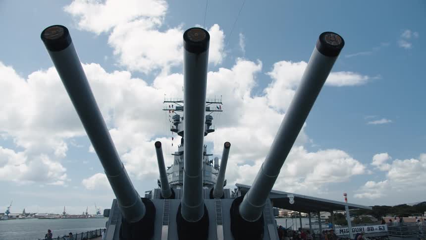 Military ship sits in the harbor under the white clouds