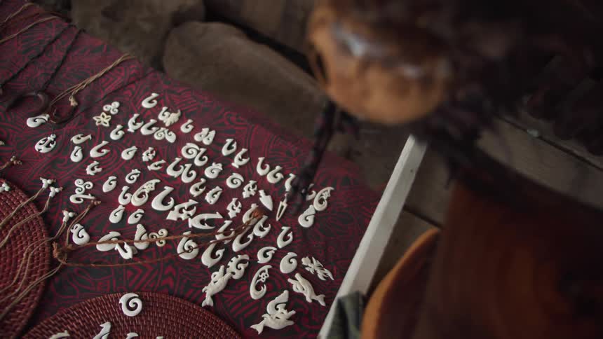 Carved pacific islands style jewelry sits on cloth covered table