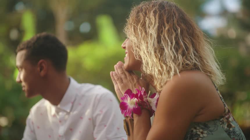 A woman claps her outside in a park setting beside a man