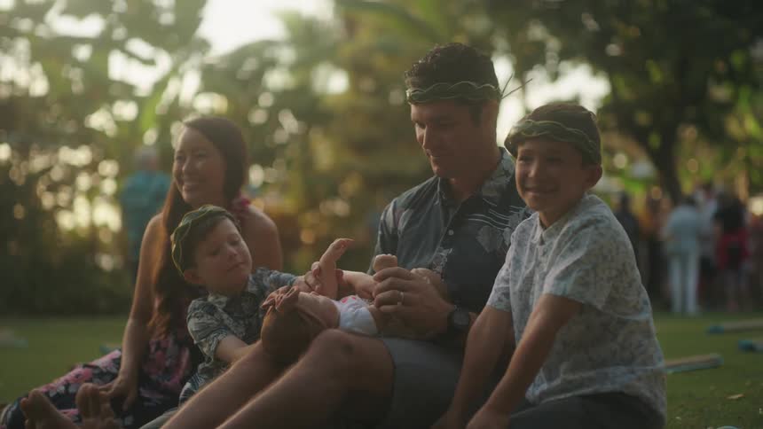 A family sits and plays together in a grassy park area