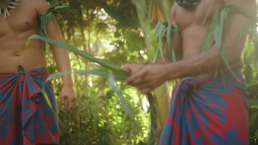 Polynesian men braid vegetation while standing outside