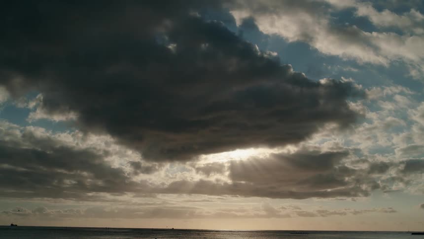 Sun rays streaming through gaps in clouds over the sea