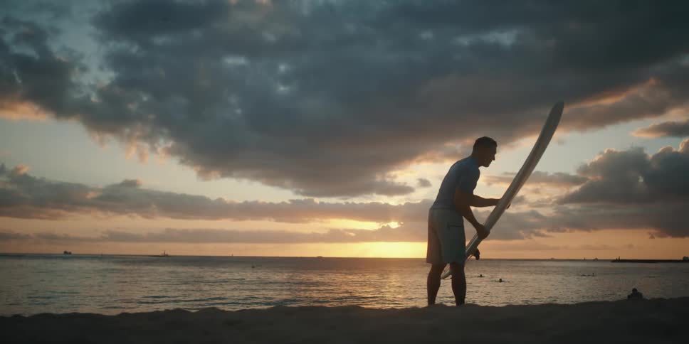 A man is holding a surfboard by the beach coast