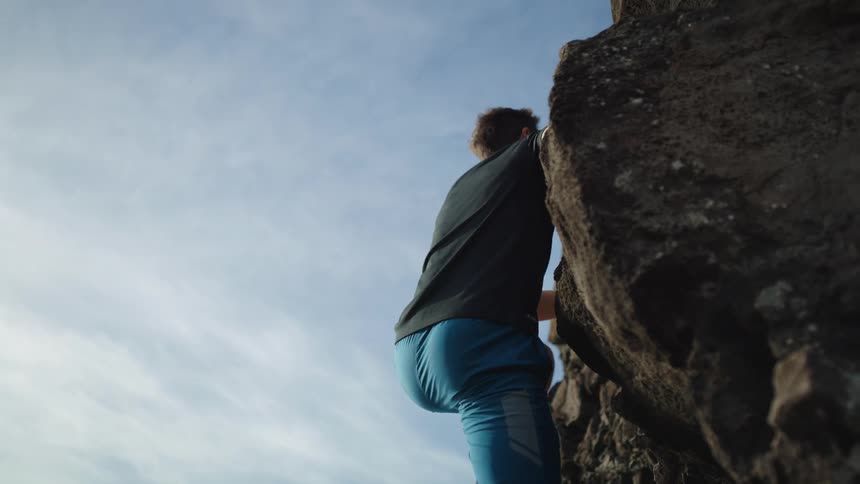 Close up of a male climbing the edge of a cliff