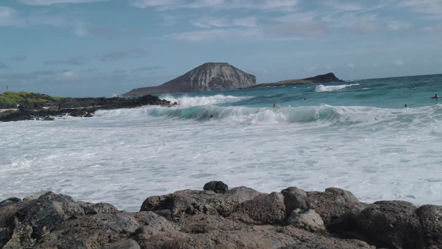 Surfers riding waves in beach near island