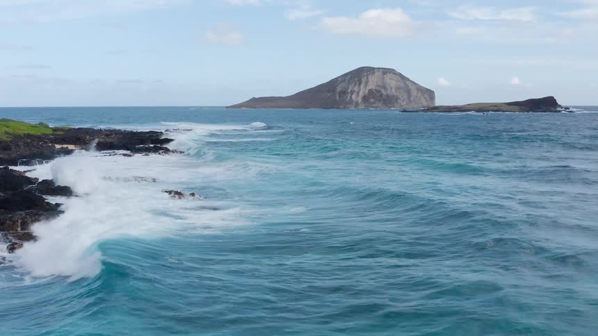 Ocean waves crash against the rocky shore on a cloudy day