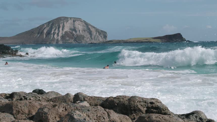 A surfer body surfs a wave in while others wait to paddle out
