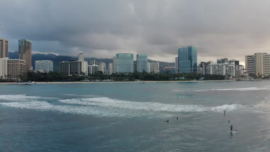 A city near the coast with people surfing and paddle boarding on the water