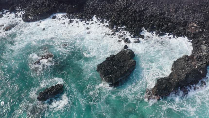 Aerial view of waves crashing against the shore during daylight