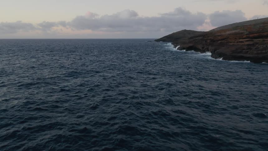 Waves ripple on an ocean surface at sunset