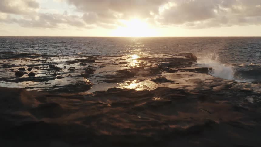 Waves crash onto the shore at sunrise