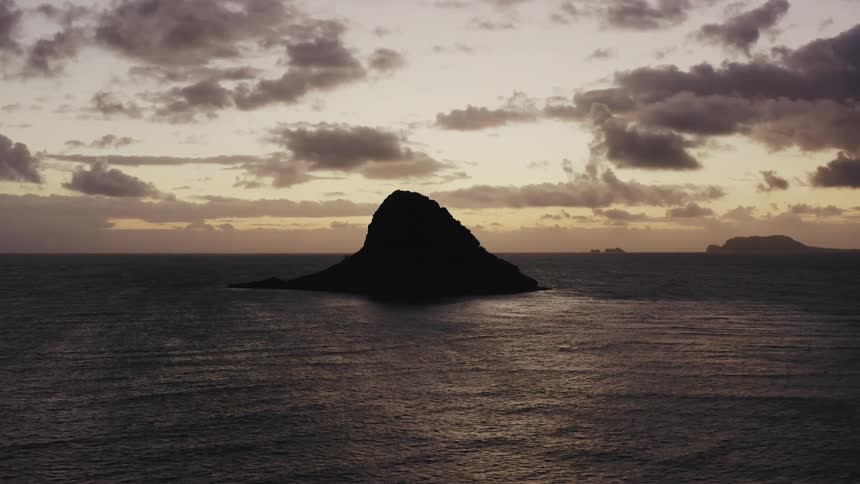 A rock island in the ocean at sunset