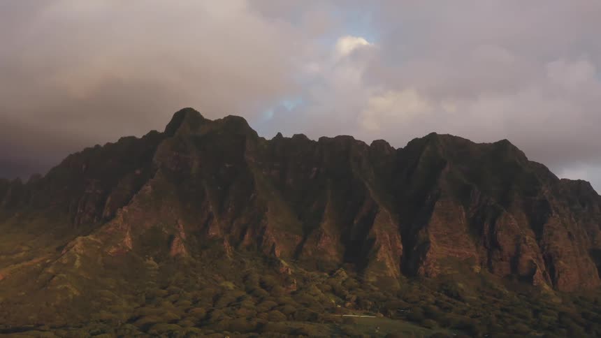 Steep mountain range under clouds a sunset
