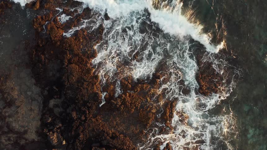 The waves crash into the rocks
