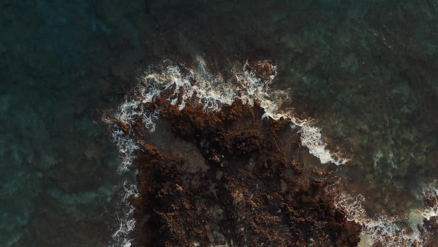Birds eye view of waves crashing on rocks