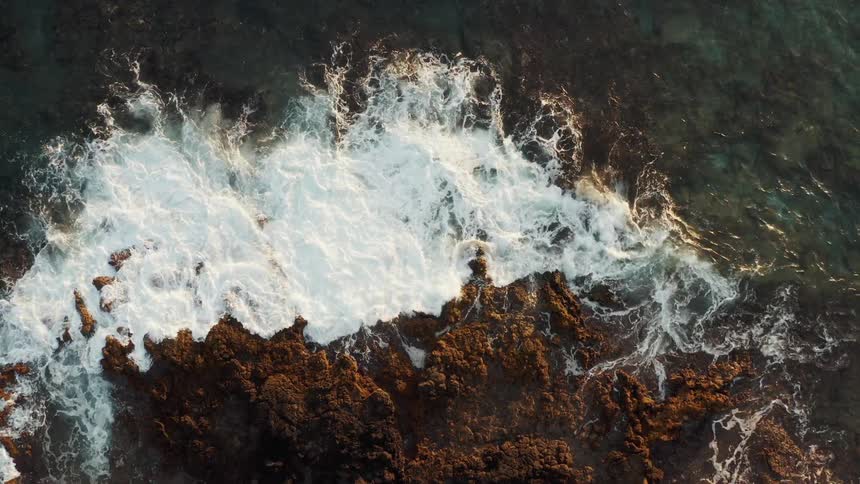 Ocean waves crash into a rocky island