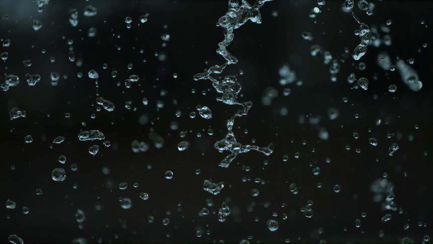 Water drops slowly falling and reflecting light