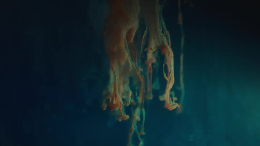 Blue and orange liquid suspension in dark blue water