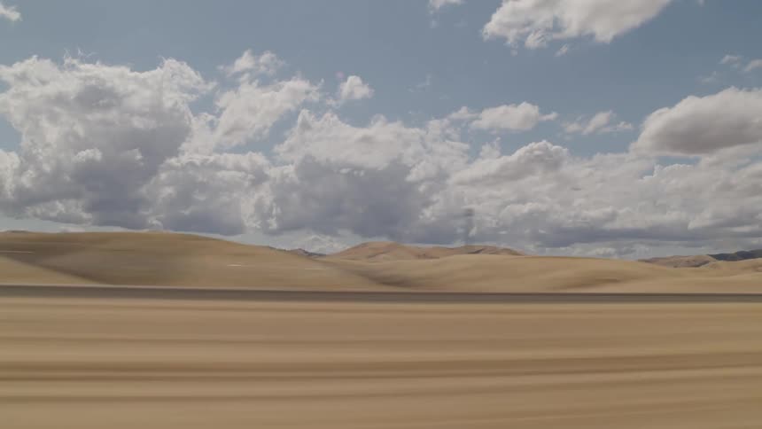 White clouds float over the sandy desert