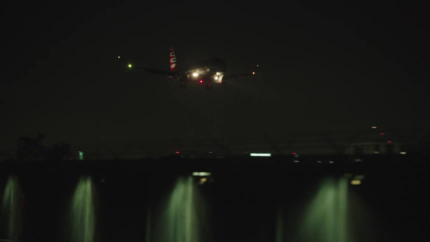 Cars drive along a street as an airplane lands
