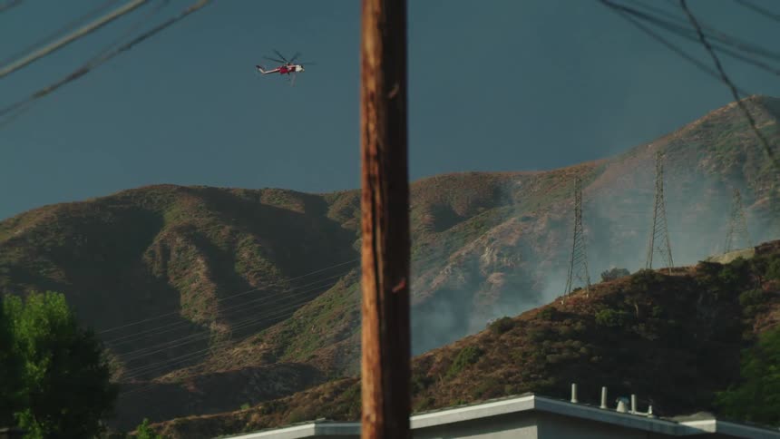A helicopter travels over the top of the mountains