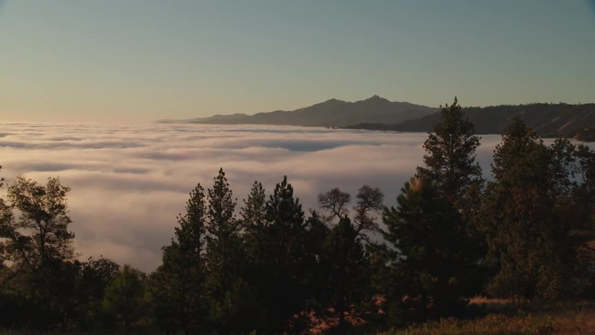 A thick layer of fog covers the area between two hills and ridges