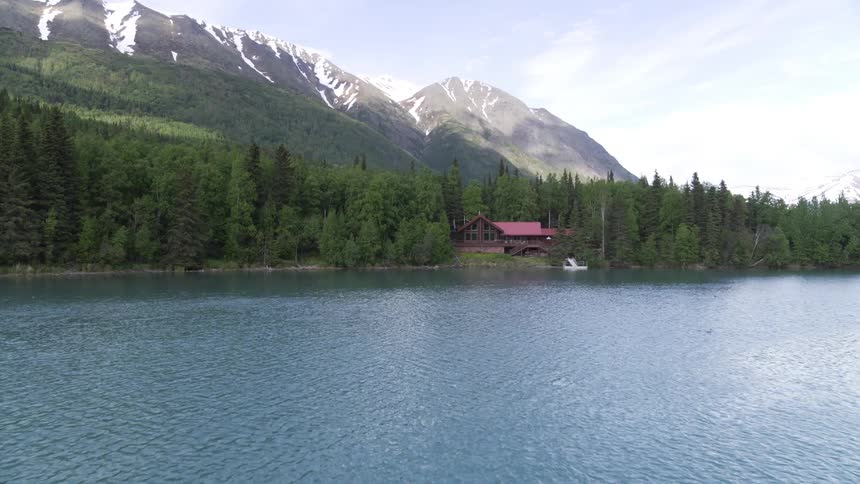 Large lakeside cabin in front of rugged mountain range