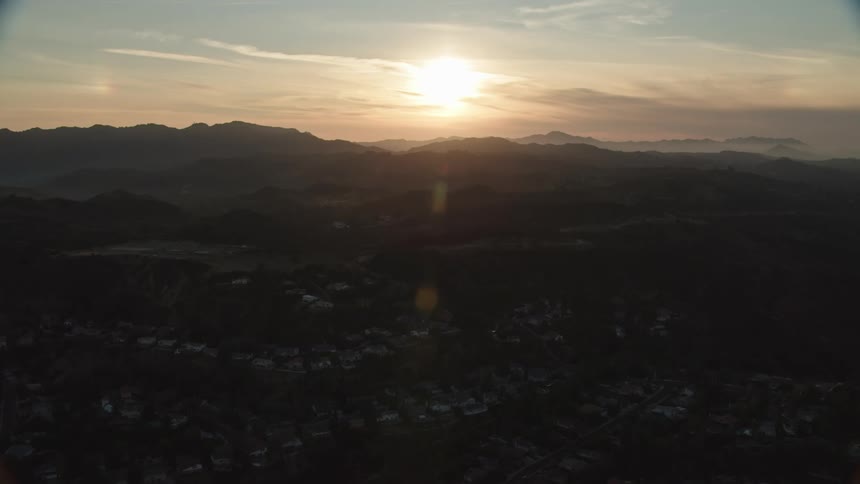 Sun rises over mountain range with fog