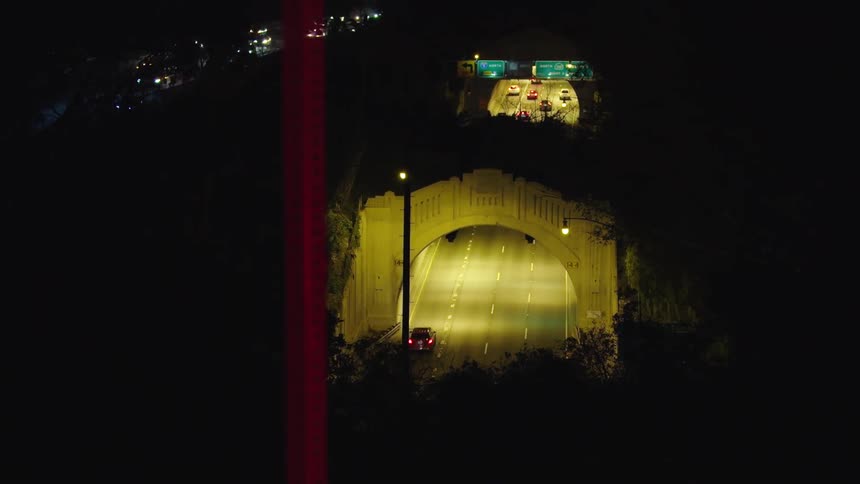 The vehicles drive through the tunnel at night