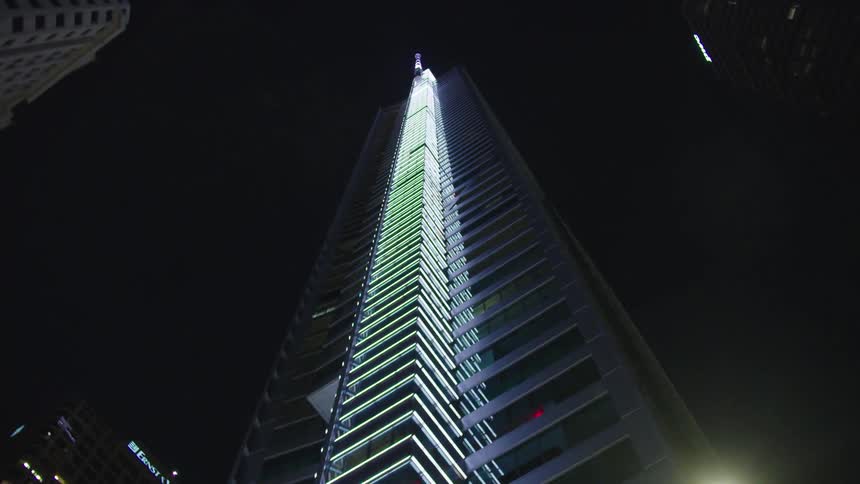 Large skyscraper at night with fluorescent lighting up side