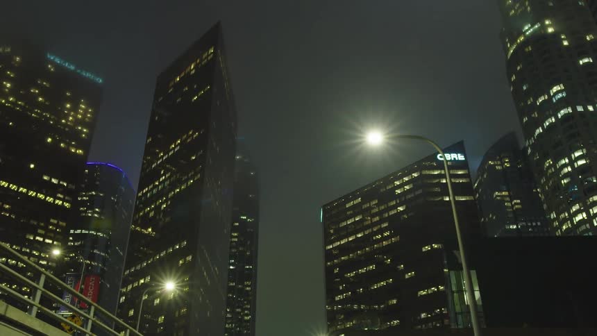 Tall skyscrapers in city at night from street view tilting up