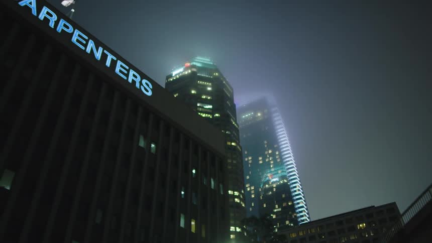 Skyscraper lights reflects on clouds over city downtown