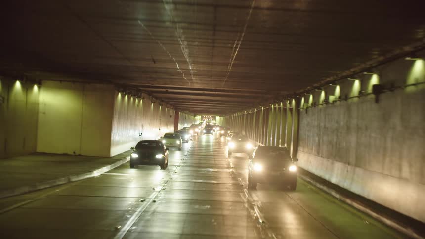 Cars travel down a busy highway under a bridge