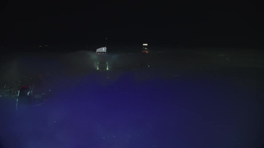 Skyscrapers peeking over clouds at night