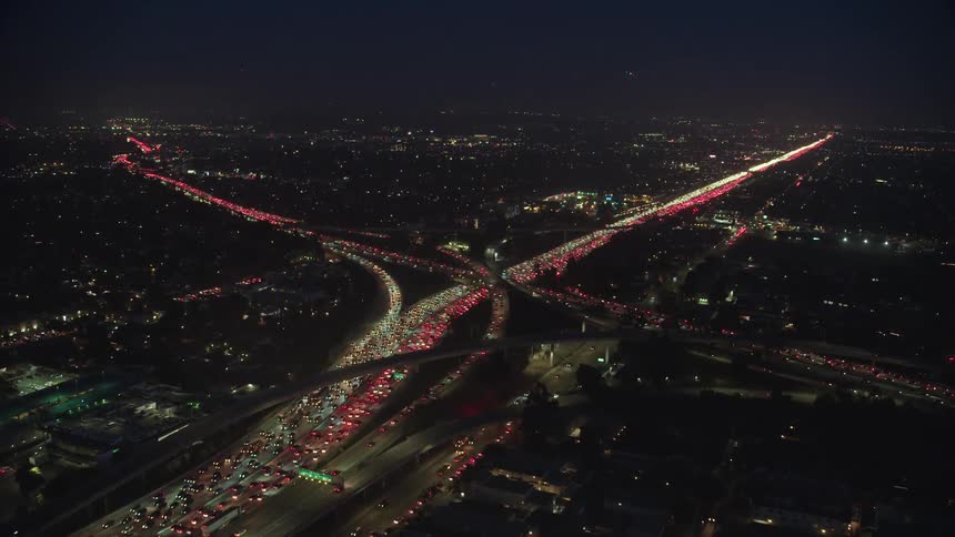 Cars drive down a busy freeway at night