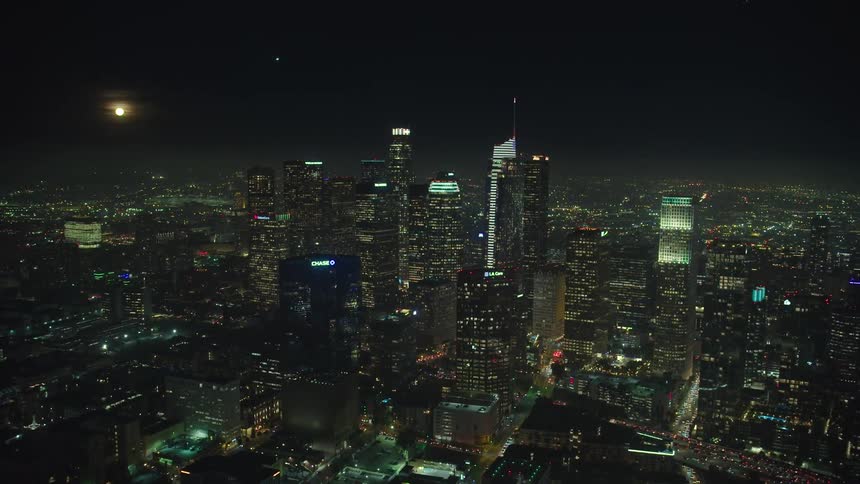 Aerial view of the illuminated city with tall buildings and skyscrapers at night