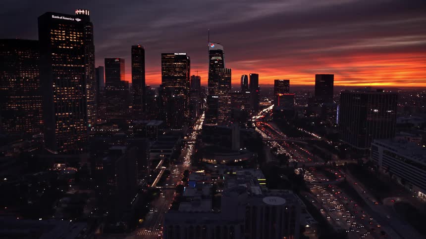 Aerial view of traffic jam and illuminated tall buildings with skyscrapers at dusk