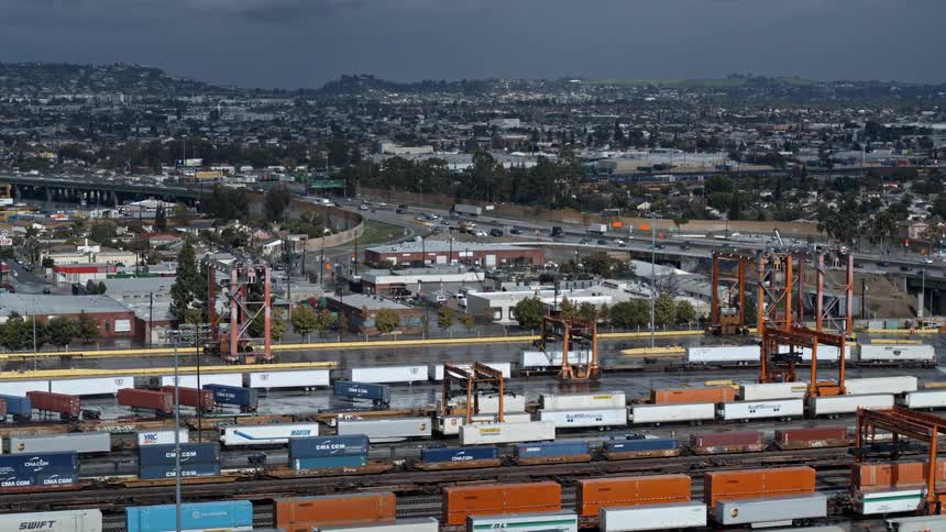 Wide shot of shipping yard with freeway and city in background