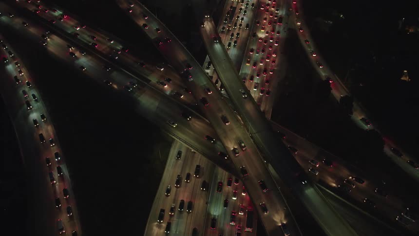 An aerial view of vehicles are driving on a highway at night