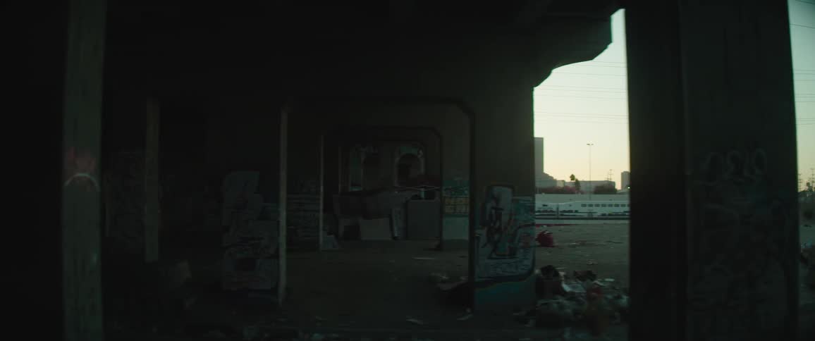View of city skyline past graffiti covered bridge and industrial lot