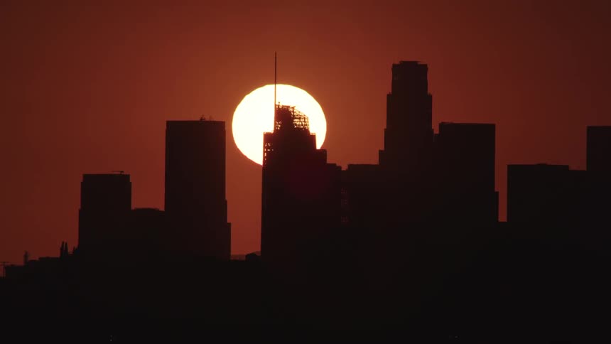 A city skyline with buildings and skyscrapers with the sky and the sun in the background