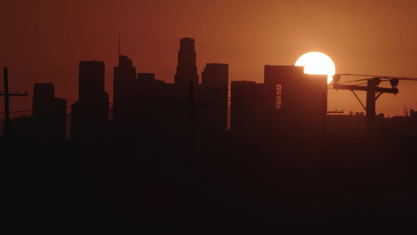 The sun sets behind a city