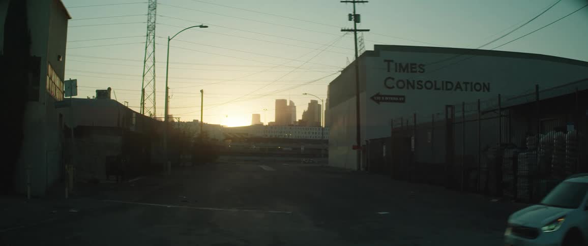 Sun peaks over the horizon near downtown as a car drives past an intersection