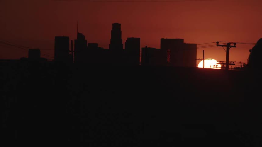 The sun sets behind a city