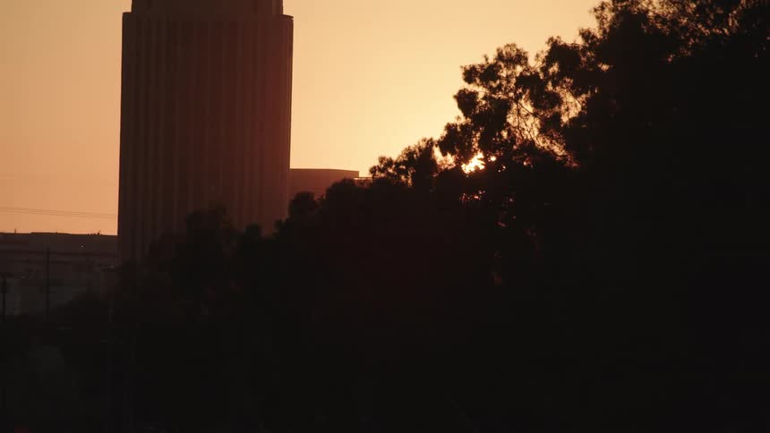 The sun sets behind a silhouette city