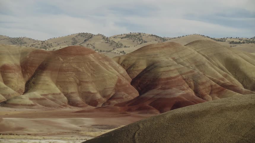 Striations mark desert rocky hills while brush dots others