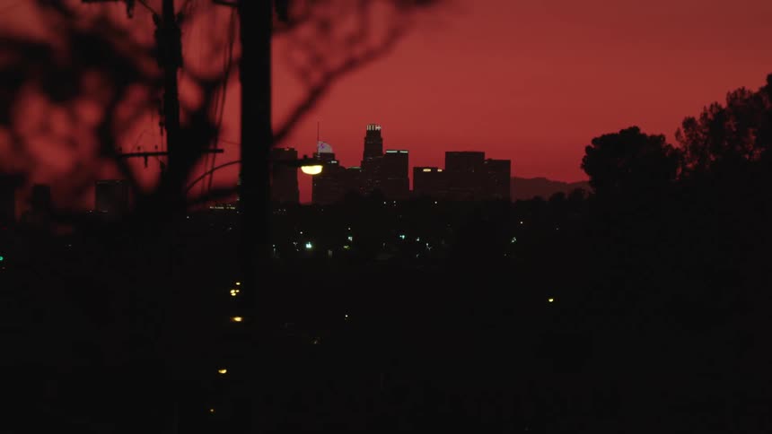 City buildings sit under the night red sky