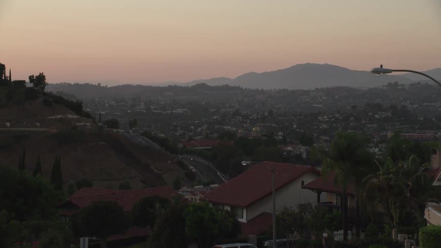 Homes on hillsides overlooking roads and valley neighborhood at sunset