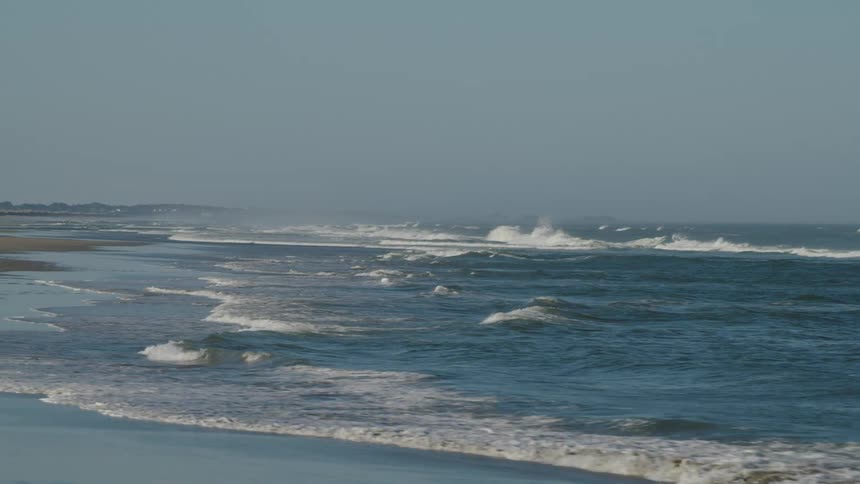 Waves roll in off the ocean onto a sandy beach