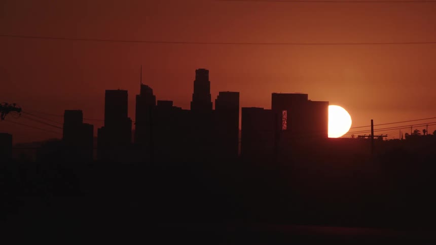 A city skyline with the sun and the sky in the background